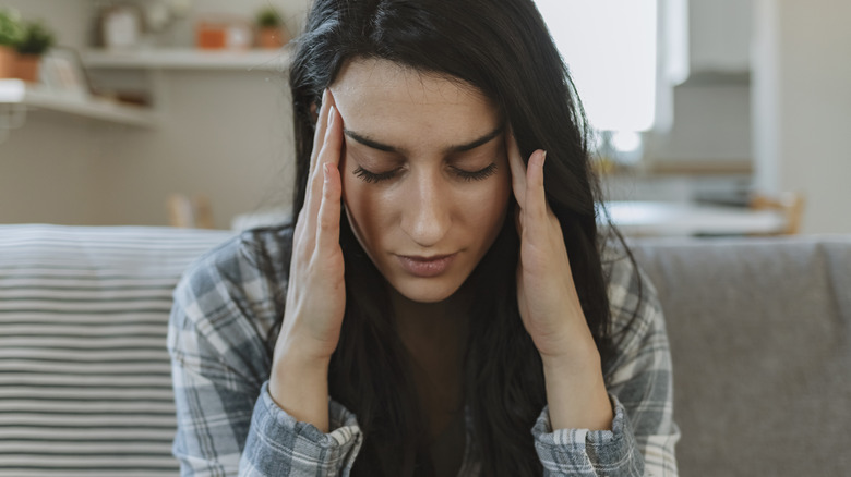woman rubbing temples to relieve migraine